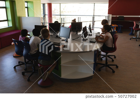 Group of schoolkids studying on desktop pc in school Group of schoolkids studying on desktop pc in school 50727002