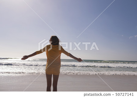 Woman standing with arms outstretched at beach 50727141
