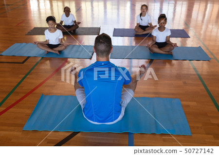 Yoga teacher teaching yoga to school kids in school 50727142