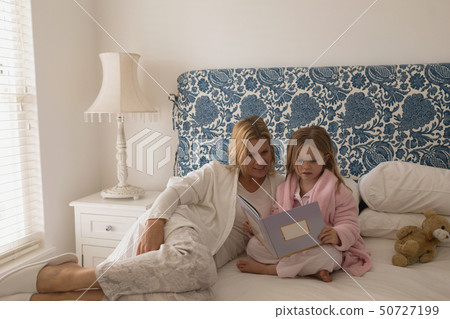 Mother with her daughter reading storybook in bedroom Mother with her daughter reading storybook in bedroom 50727199