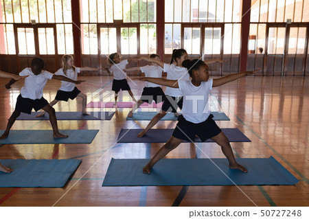 Schoolkids doing yoga on a yoga mat in school Schoolkids doing yoga on a yoga mat in school 50727248