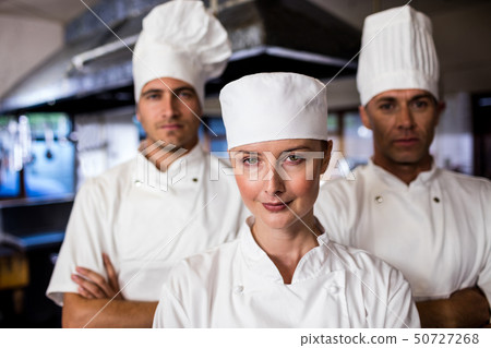 Group of chefs standing with arms crossed in kitchen Group of chefs standing with arms crossed in kitchen 50727268