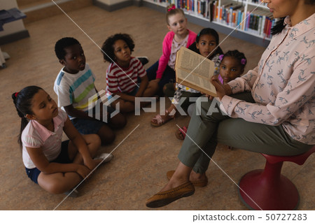 Female teacher reading a story to schoolkids 50727283