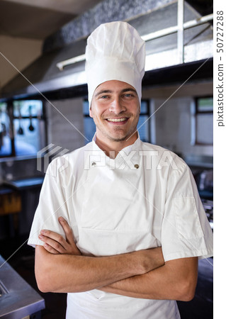 Male chef standing with arms crossed in kitchen 50727288