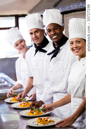 Group of chefs holding plate of prepared pasta in kitchen 50727296