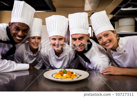 Group of chefs looking at prepared pasta in kitchen Group of chefs looking at prepared pasta in kitchen 50727311
