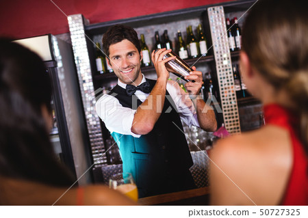 Bartender shaking cocktail in cocktail shaker at bar counter 50727325