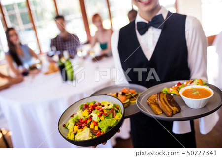 Waitress holding food on plate in restaurant Waitress holding food on plate in restaurant 50727341