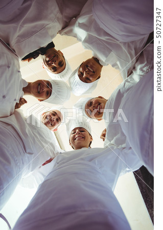 Group of chefs formig huddles in kitchen Group of chefs formig huddles in kitchen 50727347