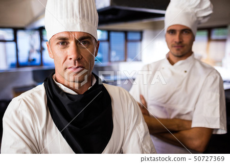 Two male chefs standing with arms crossed in kitchen Two male chefs standing with arms crossed in kitchen 50727369