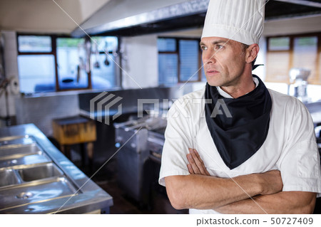 Male chef standing with arms crossed in kitchen 50727409