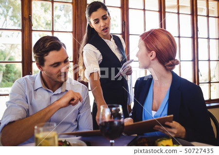 Business people discussing menu card with waitress 50727435