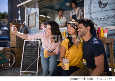 Friends taking selfie from mobile phone in food truck van 50727436