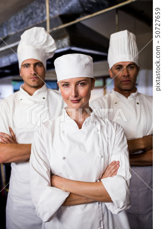 Group of chefs standing with arms crossed in kitchen Group of chefs standing with arms crossed in kitchen 50727659