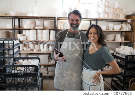 Smiling potter colleagues using tablet pc looking at camera 50727696