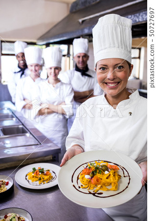 Group of chefs holding plate of prepared pasta in kitchen 50727697