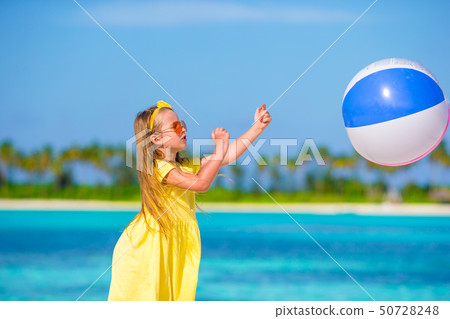 Little adorable girl playing on beach with ball 50728248
