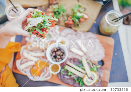 Fresh bruschettes, cheeses and meat on the board in outdoor cafe with amazing view in Manarola Fresh bruschettes, cheeses and meat on the board in outdoor cafe with amazing view in Manarola 50733336