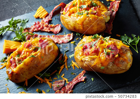 Loaded freshly Baked Potatoes on a stone tray Loaded freshly Baked Potatoes on a stone tray 50734283
