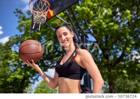 Beautiful sexy fitness girl in black sport wear with perfect body with basket ball at basketball 50736724