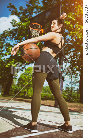 Beautiful sexy fitness girl in black sport wear with perfect body with basket ball at basketball 50736737