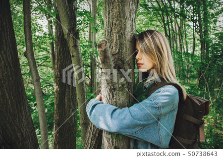 woman with backpack hugging a tree in forest  50738643