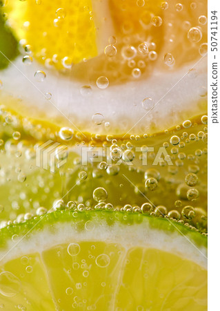 Ripe sliced pieces of lemon and lime in a glass with water and bubbles. Macro photo of summer 50741194