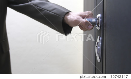 Closeup of male hand unlocks a house's door 50742147