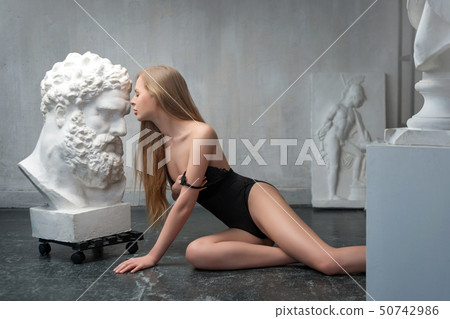 Young woman kissing Heracles head sculpture, plaster copy of a marble statue. Son of Zeus, the Young woman kissing Heracles head sculpture, plaster copy of a marble statue. Son of Zeus, the 50742986