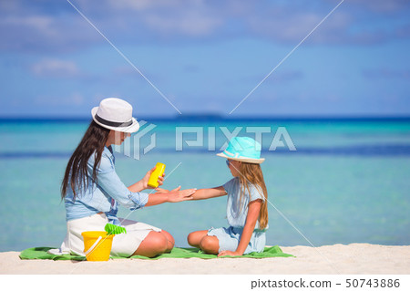 Young mother applying sunscreen on her kid Young mother applying sunscreen on her kid 50743886