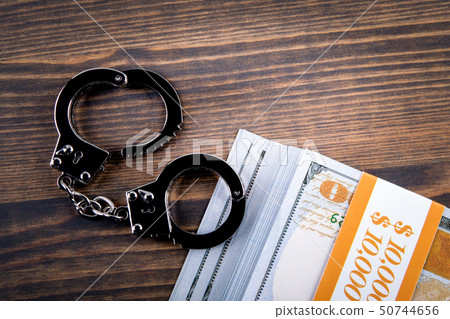 Handcuffs with money on a dark wood background 50744656