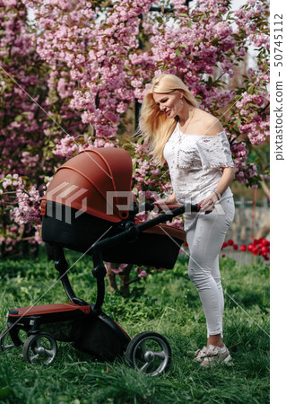 beautiful young mother with a baby carriage walks 50745112