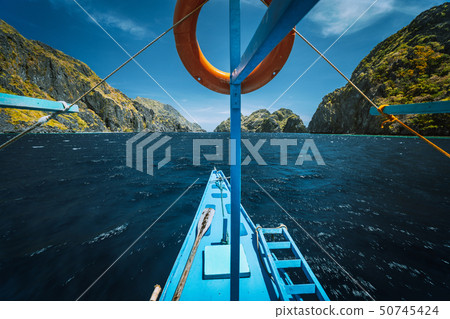 Island hopping banca on tour C between Tapiutan and Matinloc Island. Limestone cliffs and ocean 50745424