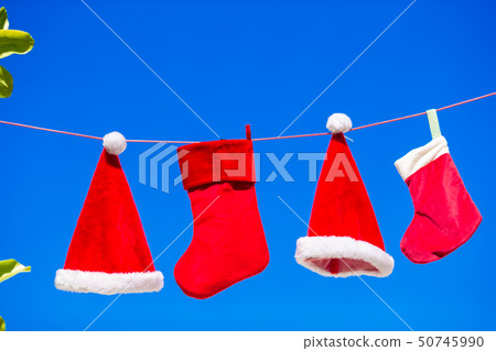 Red Santa hats and Christmas stocking hanging on tropical beach Red Santa hats and Christmas stocking hanging on tropical beach 50745990