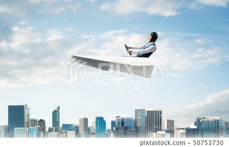 Aviator driving paper plane above business center Aviator driving paper plane above business center 50753730