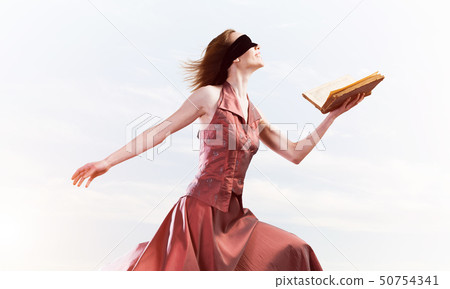 Girl against cloudy sky with opened book in palm as idea for knowledge 50754341