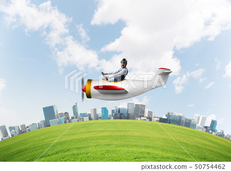 Aviator driving propeller plane above city Aviator driving propeller plane above city 50754462