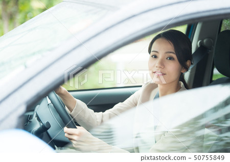 A woman driving a car 50755849