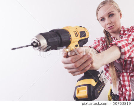 Woman using drill on wall Woman using drill on wall 50763819