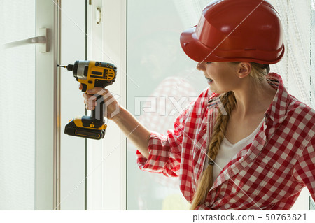 Woman using drill on window 50763821