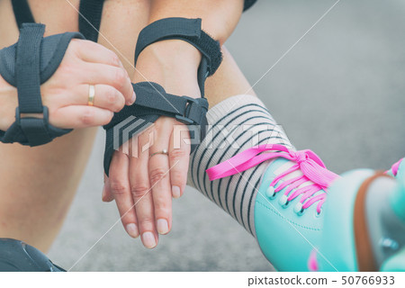 Woman rollerskater putting on wrist guards 50766933