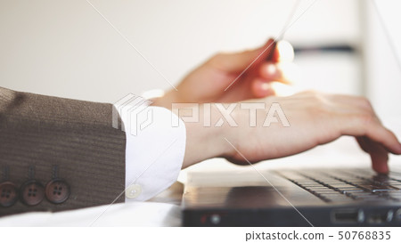 Man enters credit card information for online purchases while working on laptop Man enters credit card information for online purchases while working on laptop 50768835