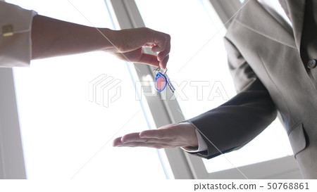 Real estate agent handing over a key to a customer on the window background Real estate agent handing over a key to a customer on the window background 50768861