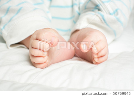 嬰兒的頭髮和腳趾在白色的被子上 嬰兒的頭髮和腳趾在白色的被子上 50769945