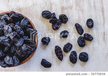 Dark blue raisins in a wooden bowl on a bright 50770656