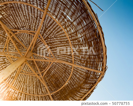 Image of straw umbrellas on the ocean beach at hot sunny day against blue sky 50778755