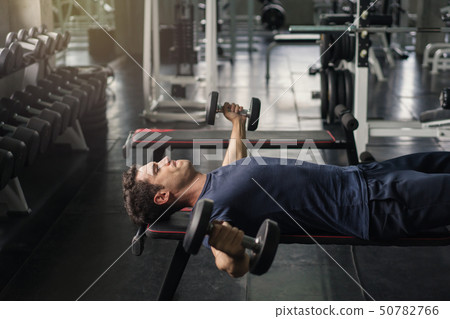 Handsome weightlifter lifting bench press working Handsome weightlifter lifting bench press working 50782766