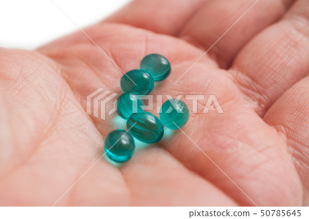 closeup of blue pills in hand on white background 50785645