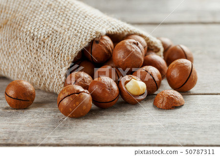 Macadamia nut on a wooden table in a bag, closeup, 50787311