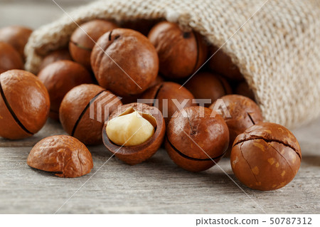 Macadamia nut on a wooden table in a bag, closeup, 50787312